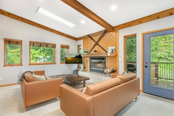 Living room with door to back deck, surrounded by open space, nature and gorgeous views.