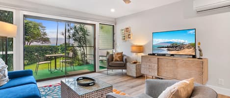 Living Room with large sliding door to lanai, overlooking the ocean, big screen TV and split AC