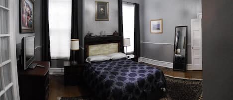 Bedroom with Queen bed, TV, closet with iron and ironing board, pedestal fan