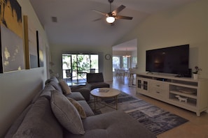 Living room with 65" TV overlooking outside patio and backyard