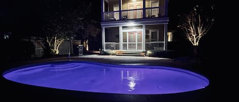 Wonderful outdoor entertaining area offering uplit trees and landscaping, a gas heated pool with outdoor table and chairs set, lounge chairs, a propane grill and an outdoor heated shower station.