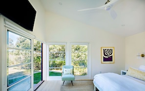 Master bedroom with lots of glass, natural light, ceiling fan, flat screen TV.