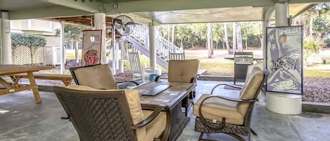 the covered car port has a picnic table, firepit table, gas grill, rockers and corn hole!