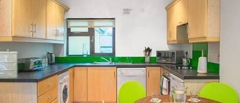 Fully fitted well equipped kitchen has crockery and utensils with oven, hob, microwave, dishwasher, washer/drier