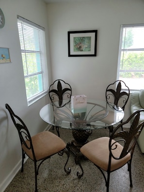 Glass dining table seating for four. Kitchen has extra bar seating.