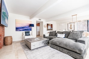 The main living area features a large sofa with streaming TV, fireplace, and sliding glass doors that open to the patio.