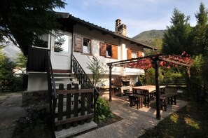 The home Carla garden with a pergola with BBQ place, table and wooden banks