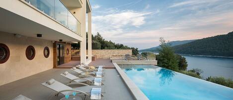 Sunbathing area near private pool with deck chairs of Labin seafront Croatian luxury villa for vacation and rent.
