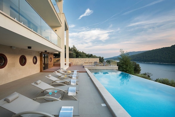 Sunbathing area near private pool with deck chairs of Labin seafront Croatian luxury villa for vacation and rent.