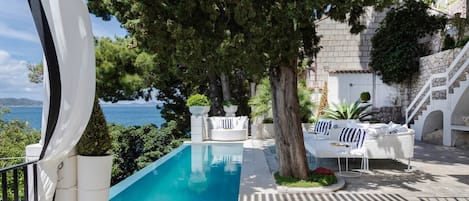 Terrasse der Kroatien luxuriösen Strandvilla mit Esstisch und Sitzbereich am Pool