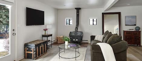 Living room with new flooring, wood-burning stove and access to the backyard.