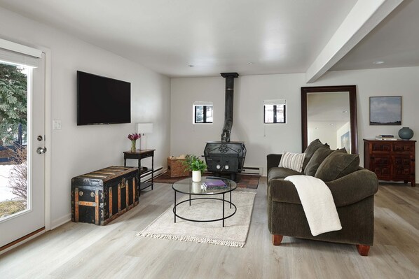 Living room with new flooring, wood-burning stove and access to the backyard.