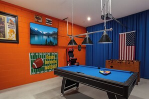 Games room showing pool table, TV and decor.