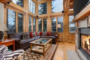 Living Room with vaulted ceilings, stunning windows that allow for an abundance of natural light, leather furnishings, full sofa-bed, gas fireplace, and 55" Vizio TV