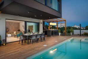 Fenced yard of the luxurious Dalmatian villa for rent and vacation with an outdoor dining table and a private pool in Rogoznica