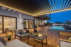 Outdoor seating area with a coffee table in the covered part of the patio nex to the private illuminated pool in front of the luxury dalmatian villa in Rogoznica