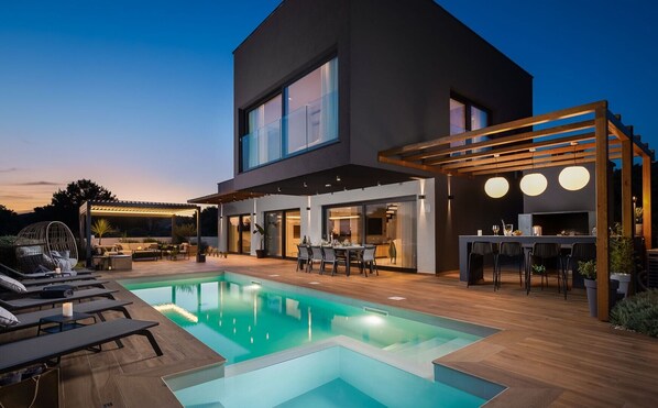 Spacious patio with an illuminated pool in front of the entrance to the luxury Croatian villa Indigo near Rogoznica