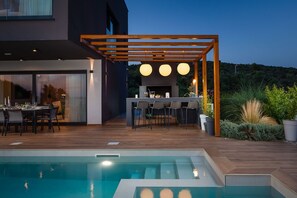 Outdoor dining table with chairs next the barbecue on the spacious patio of the pet-friendly Croatia vacation home Indigo