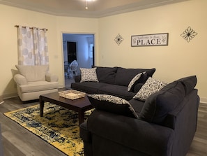 Updated flooring and furniture—sofa, loveseat, and oversized chair. 