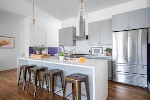 Kitchen features an island with barstool seats and modern appliances.