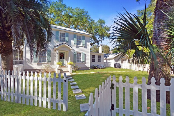 Classic St. Simons Beach Cottage with Fenced Yard - Palm trees, a white picket fence, and a sunlit path that leads you home—this St. Simons vacation rental gets the curb appeal exactly right.