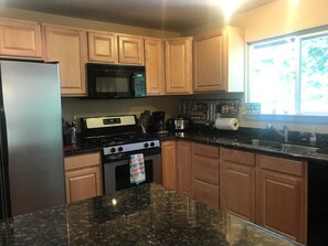 Kitchen with gas stove, microwave, dishwasher, coffee pot, dishes, etc.