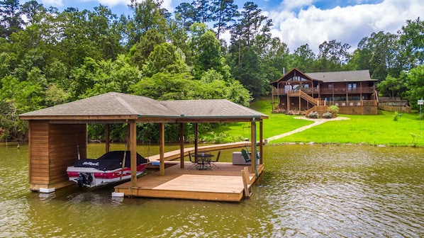 large grassy backyard with stone pathway from main home to boathouse .and lake