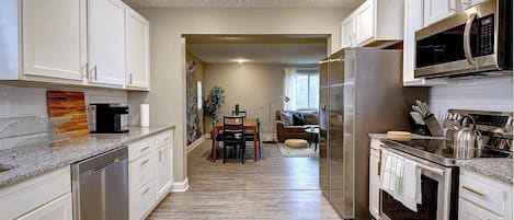 Spacious kitchen with granite counters, subway tile backsplash and appliances.