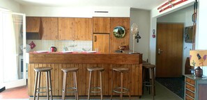 Sunny and bright open bar kitchen overlooking the terrace and the mountains. 