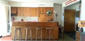 Sunny and bright open bar kitchen overlooking the terrace and the mountains. 