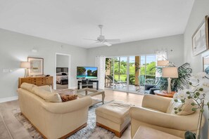 The family room has leather furnishings, a TV and access to the screened lanai