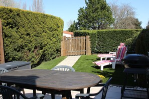 Terrasse avec table, fauteuils, barbecue