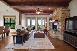 Main living room area w/ large leather sofa and chair facing a cozy fire place.