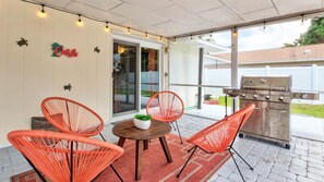 Enjoy outdoor dining by the grill with seating for 4, overlooking a covered pool nestled in beautiful greenery.