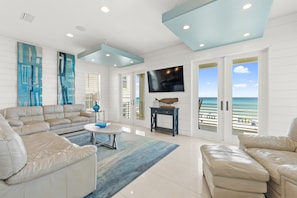 Living Room | Breathe Easy Rentals - Enjoy the crisp white shiplap walls accented with all the beautiful blues and turquoise colors while lounging on the plush, comfy leather furniture. Aww, tranquility!