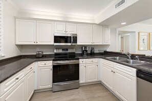 The open Kitchen has stainless steel appliances and crisp, white cabinets.
