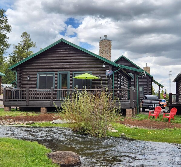 Back side of cabin facing  ponds & meadow area. Just below the Adirondack chairs is  Little Colorado River. A nice place to sit & fish or just enjoy the fresh air. Our porch has 3 cafe  tables and six padded chairs next & propane grill. Gas provided.