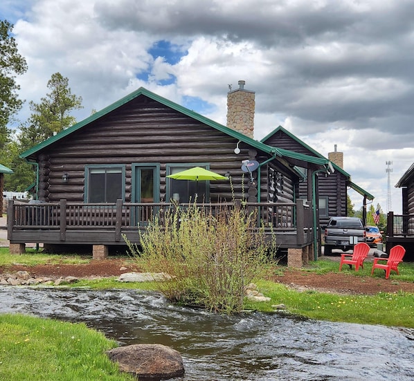 Back side of cabin facing ponds & meadow area. Just below the Adirondack chairs is Little Colorado River. A nice place to sit & fish or just enjoy the fresh air. Our porch has 3 cafe tables and six padded chairs next & propane grill. Gas provided.