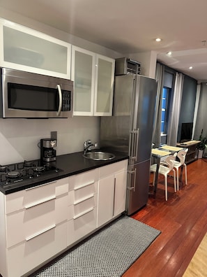 Kitchen with gas stove, microwave, full size refrigerator, dishes and cookware