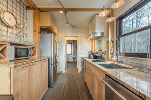 Sleek kitchen with stainless appliances, dishwasher, and farmhouse sink.