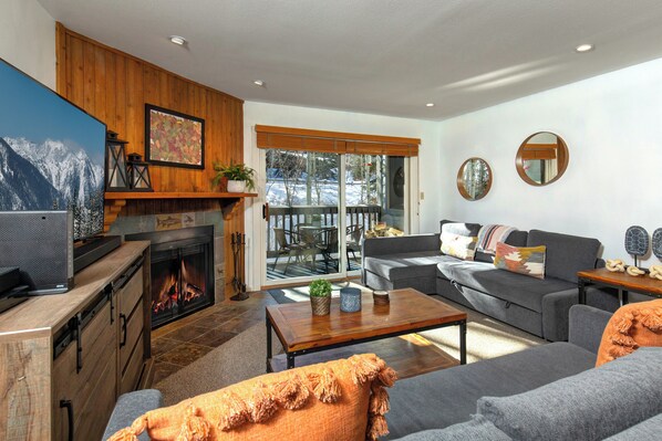 The living room has comfortable couches, gas burning fireplace and views of the aspen grove.