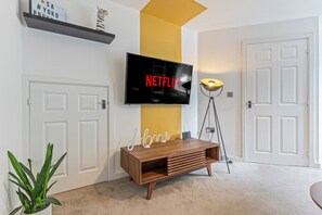 A cosy living room featuring a large corner sofa, arm chair and a 50'' Smart TV with Netflix subscription included