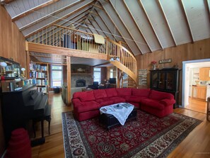 Large living room with 2 separate sitting areas, fireplace and a piano.