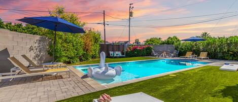 Gorgeous private backyard featuring a heated pool & spa, cabana, sun loungers, BBQ grill, outdoor dining, fire pit, cornhole and putting green.
