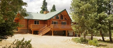 Surrounded by trees, large circular driveway, steps to deck and front door