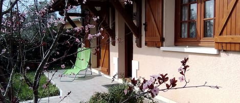 Façade de la maison avec jardin clôturé et petit terrasse 