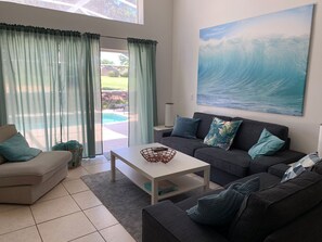 Living room with TV and access to pool area.