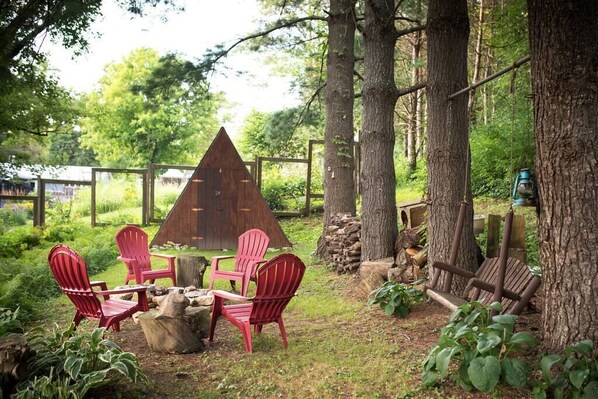 Backyard hill with fireplace and wooden swing.