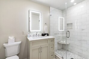 Side 1: Ensuite Primary Bathroom 1 featuring large frameless glass Italian marble shower. Enjoy plush towels, blow dryer and complimentary shampoo, conditioner, body wash, tooth brushes (2), tooth paste, mouth wash, lotion and makeup remover wipes.