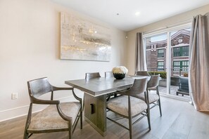 Side 1: Open-concept living, kitchen, and dining area with ample seating. Enjoy a 65” Samsung Smart 4K TV with streaming and DIRECTV Entertainment. Relax on the sofa and cozy chairs, dine at the table for six, and enjoy the natural light!